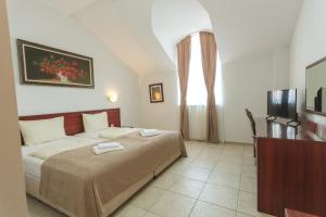 a bedroom with a bed and a television in it at Hotel CENTRAL Balchik in Balchik