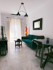 Una sala de estar con un sofá verde y una mesa. en Conil Alojamientos Manrey, en Conil de la Frontera