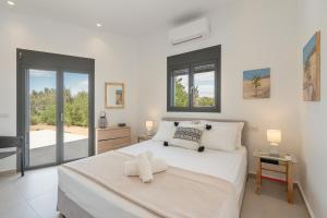 a white bedroom with a large white bed with windows at Green & Purple in Khlóï