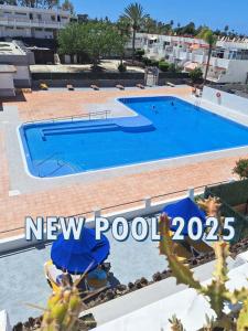 een zwembad in een resort met een bord met een nieuw zwembad bij EL CHAPARRAL Studio-appartement with fantastic pool- view and STRONG WIFI in Costa Del Silencio