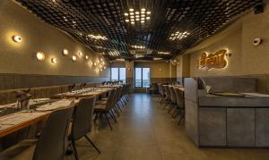 Un comedor con mesas largas y sillas. en Treebo Eden Park, Ahmedabad, en Ahmedabad