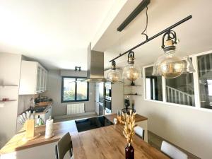 kuchnia i jadalnia z drewnianym stołem i lampkami w obiekcie Villa Spacieuse & Moderne, Proche des Plages w mieście Saint-Briac-sur-Mer
