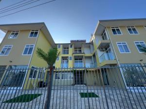 a yellow building with a palm tree in front of it at Mach Hotel in Dar es Salaam