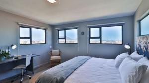 a bedroom with a bed and a desk and windows at Budapest Boutique Hotel in Edgemead