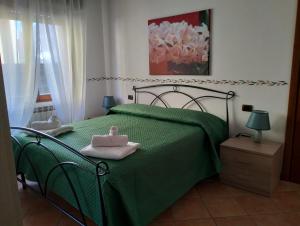 a bedroom with a green bed with towels on it at La Casa del Lago in Porlezza