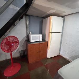 a small kitchen with a refrigerator and a red fan at La Casita de Nataly in Santa Ana
