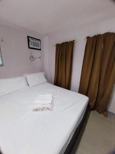 a white bed with two towels on it in a room at Abode86 Transient-Agus in Lapu Lapu City