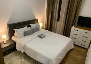 a bedroom with a white bed with a remote control on it at Les Lavandins-Yaoundé in Yaoundé +15 photos
