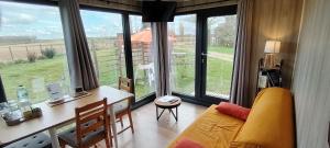 ein Wohnzimmer mit einem Sofa, einem Schreibtisch und Fenstern in der Unterkunft Chalets des prés-village in Bussy-le Repos