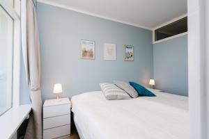 a white bedroom with two beds and two lamps at Panoramic Sierksdorf App A12-1 in Sierksdorf +20 photos