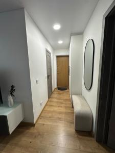 a hallway with white walls and a mirror and a chair at Apartment - Kauno 23 in Klaipėda