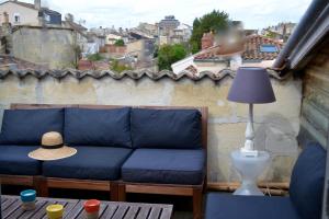 Sofá azul sentado en un balcón con sombrero en Charmant Appartement Avec Terrasse, en Burdeos