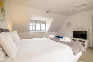 a white bedroom with a large bed and a tv at 5 Oakes Court in Thorpeness
