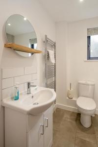 a bathroom with a sink and a toilet and a mirror at 5 Oakes Court in Thorpeness +31 photos