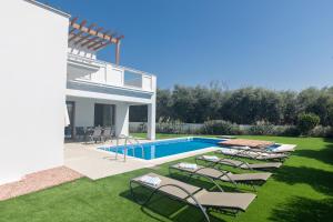 a villa with a swimming pool and lounge chairs at Sea Satin Villas - Ayia Napa Center in Ayia Napa
