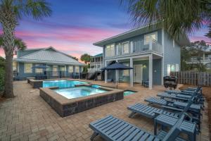 a house with a swimming pool and lounge chairs at Forever Coastal With Game Room And Private Beach in Destin