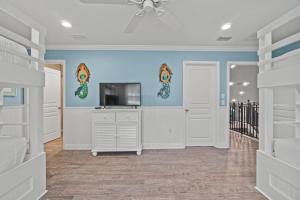 a living room with a tv and a ceiling fan at Forever Coastal With Game Room And Private Beach in Destin