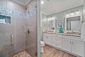 a bathroom with a shower and two sinks and a toilet at Forever Coastal With Game Room And Private Beach in Destin