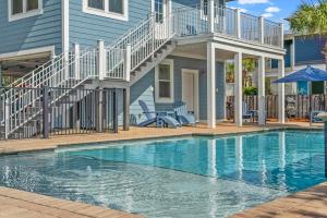 a swimming pool in front of a blue house at Forever Coastal With Game Room And Private Beach in Destin