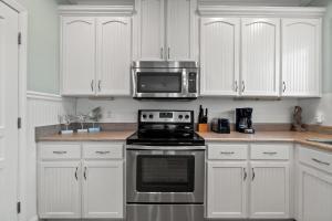 a kitchen with white cabinets and a stove and a microwave at Forever Coastal With Game Room And Private Beach in Destin