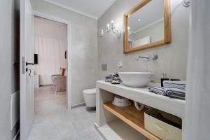 a bathroom with a sink and a toilet and a mirror at Ostria Apartments in Akrotiri +32 photos
