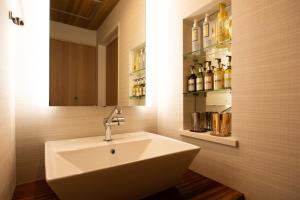 a bathroom with a sink and a shelf with bottles at HOTEL ZEN-Adult Only in Hirosaki