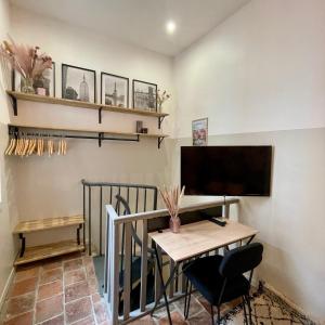 une pièce avec une table, une télévision et un bureau dans l'établissement T1 Duplex Cosy - Notre-Dame - Netflix, à Montauban