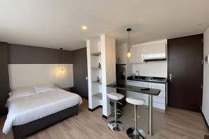 a small bedroom with a bed and a kitchen at Domus Suites Chia in Chía