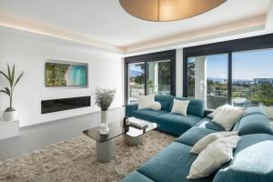a living room with a blue couch and large windows at Villa Angelique, 5 BDR with Heated Private Pool in Puerto Banus in Marbella