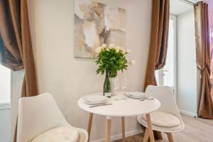 une table blanche avec des chaises blanches et un vase de fleurs dans l'établissement Nice Renting - Love Room Massena - Luxe Room - Jacuzzi - Terrace - King Bed - AC, à Nice 12 autres photos