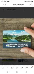 ręka trzymająca kartę ze zdjęciem jeziora w obiekcie Adler Kaprun, Golf 'n' Ski and Mountain Biking. w Kaprunie