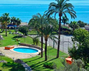 a resort with a pool and palm trees and the ocean at Sol Puerto Marina in Torremolinos