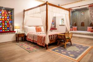 een slaapkamer met een hemelbed en een stoel bij Udaigarh - Udaipur in Udaipur