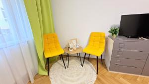 a living room with two yellow chairs and a tv at Ego Residence Alba Iulia in Alba Iulia