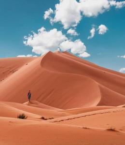 un hombre parado en la cima de una duna de arena en Merzouga Queen Luxury Camp, en Merzouga 21 fotos más