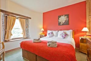 Un dormitorio rojo con una cama con toallas. en Bridge Cottages, Old Post and Bridge Suite, Sleeps 8, en Coniston