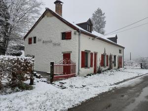 a white house with red doors in the snow at Les Arpents Verts 52 in Momignies