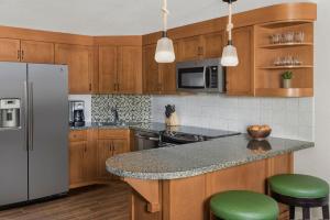 a kitchen with wooden cabinets and a counter with green stools at Marriott Grand Residences Luxury 1BD in South Lake Tahoe +27 photos