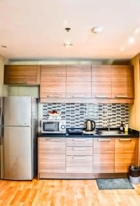 Una cocina con gabinetes de madera y un refrigerador de acero inoxidable. en Spacious and Renovated 1-Bedroom 100m to Nana BTS - 55 sqm, en Bangkok