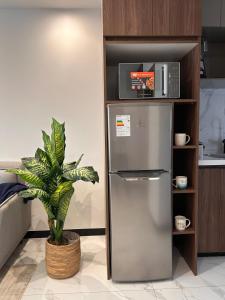 Luxury apartment with swimming pool in Equipetrol في سانتا كروز دي لا سيرا: ثلاجة ستانلس ستيل في مطبخ به نبات