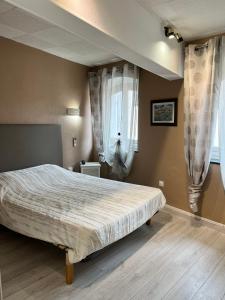 a bedroom with a large bed with drapes at Hôtel Restaurant Les Arcades in Limoux