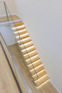 a wooden staircase with brass rail and glass treads at Arial Lofts in Vlorë