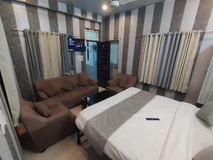a bedroom with a bed and chairs and a couch at SHARVIL Inn in Lucknow