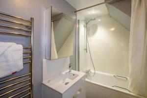a white bathroom with a sink and a shower at Sleepers Cottage in Aldeburgh +27 photos