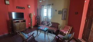 a living room with red walls and a tv and chairs at Vidala in Tilcara