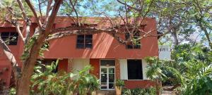a red house with trees in front of it at Serene Garden Room APT in Diani Beach