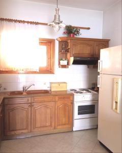 a kitchen with wooden cabinets and a white refrigerator at Traditional Maisonette House on the sea shore in Derveni +9 photos