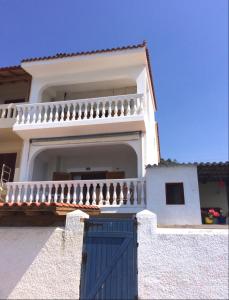 a white house with a blue door and a balcony at Traditional Maisonette House on the sea shore in Derveni