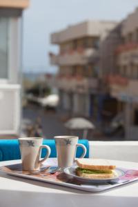 a tray with two cups and a sandwich on a table at Hostal Alemania in Es Pujols