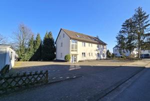 an empty street with a large white house at Keyless Boardinghouse in Bielefeld